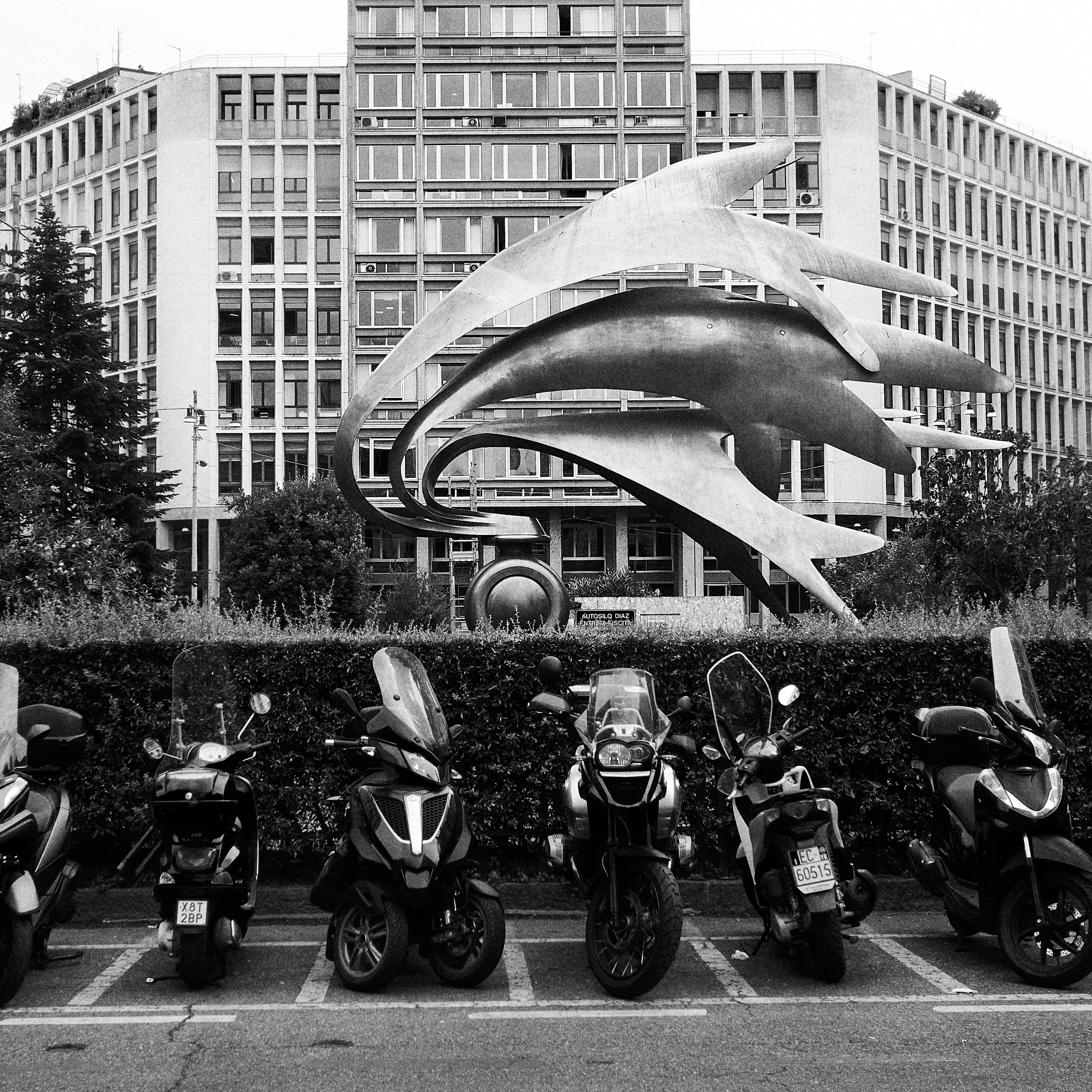 grayscale photo of motorcycle parked near building