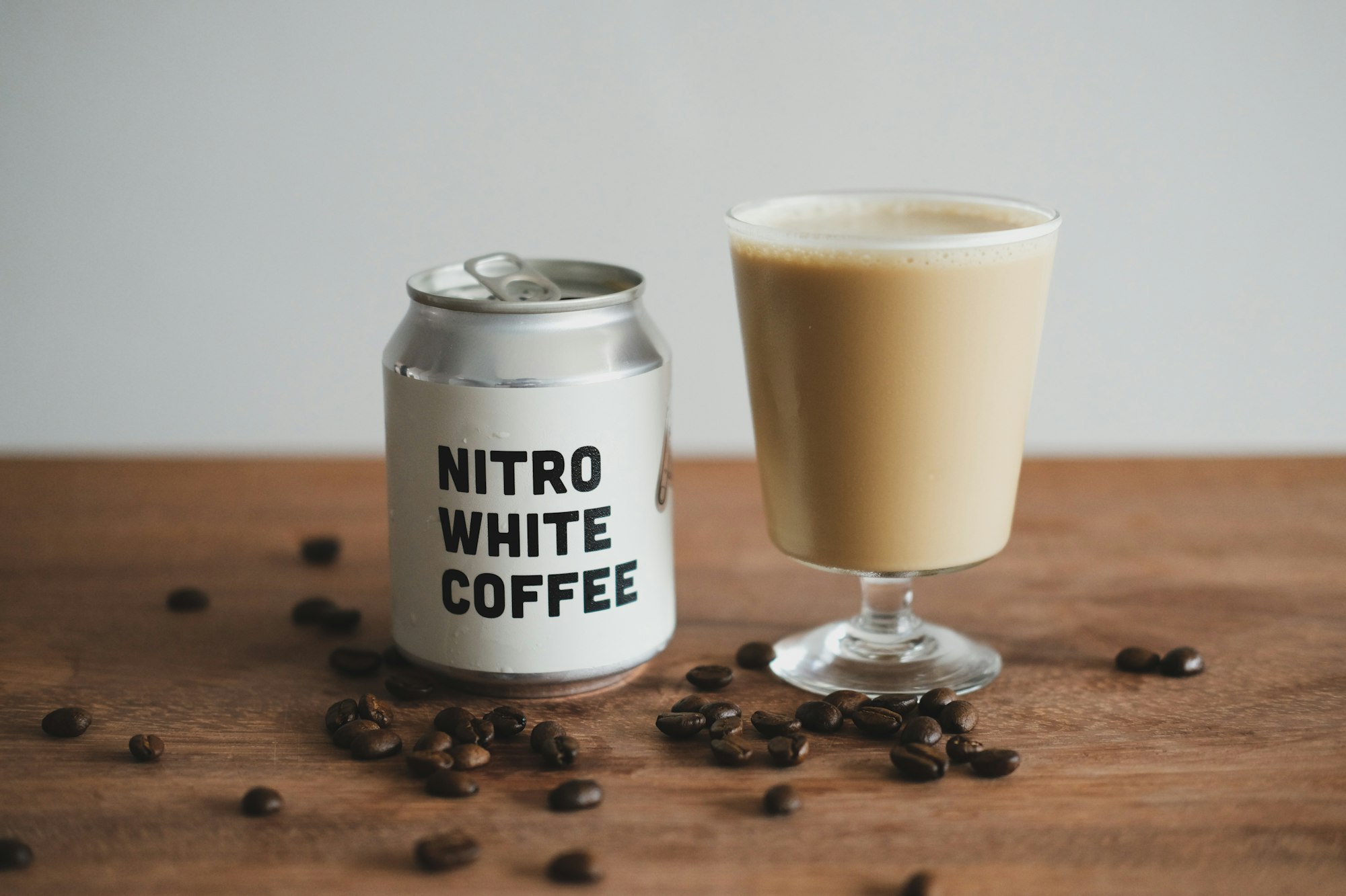 Close up shot of Pushers Nitro White Coffee, a cafe latte / flat white in a can, poured up in a stemmed glass.