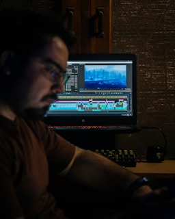 man in brown shirt sitting in front of computer
