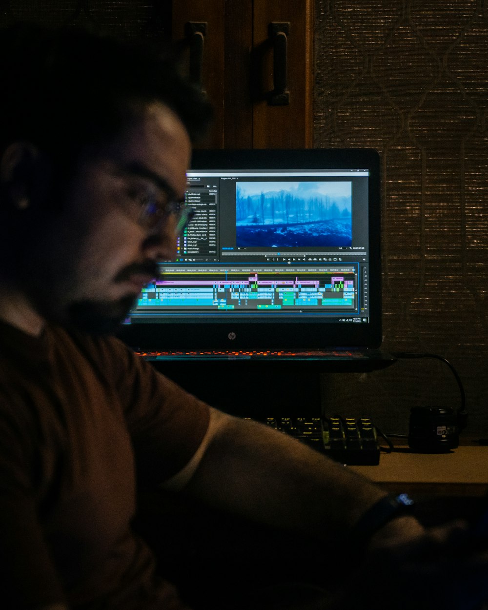 man in brown shirt sitting in front of computer