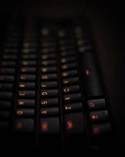 Close-up of hands typing on a laptop keyboard with a soft orange background.