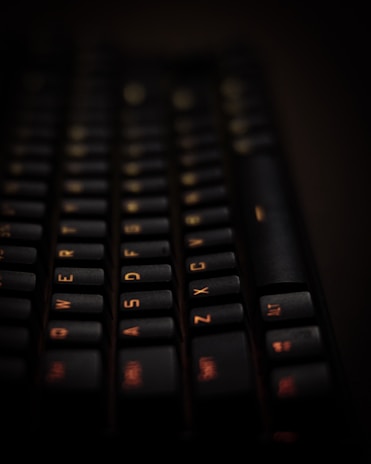Close-up of hands typing on a laptop keyboard with a soft orange background.