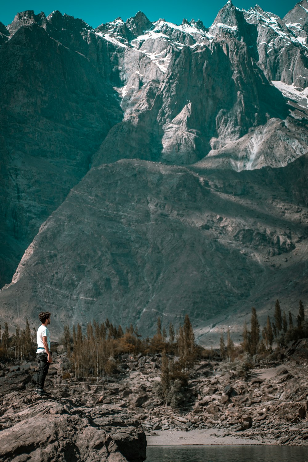 man in white shirt standing on brown grass near mountain during daytime