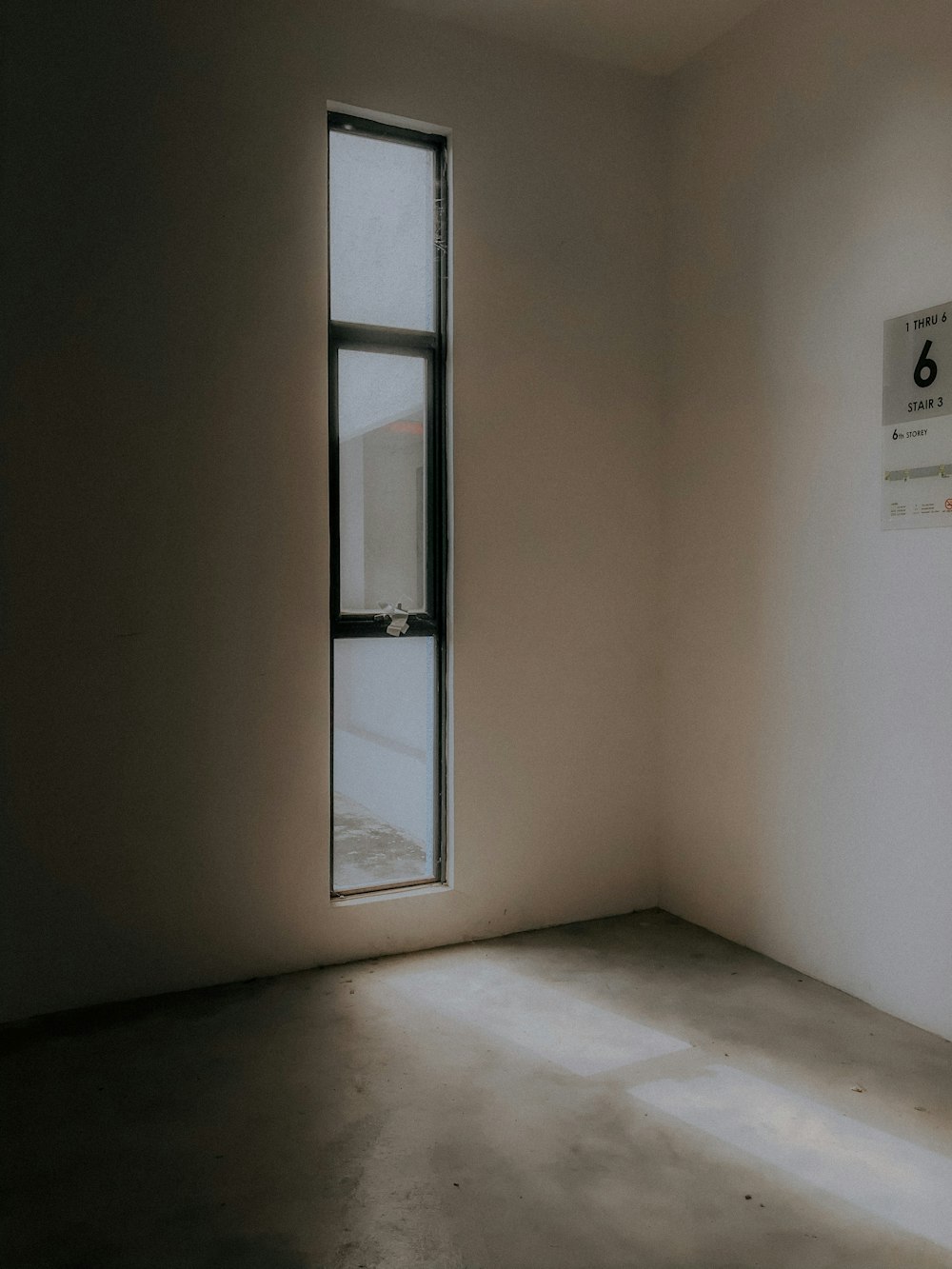 an empty room with a window and a sign on the wall