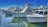 Several white boats are docked in a marina, lined up neatly along the wooden piers. The water is calm, reflecting the boats and the clear blue sky. Fishing rods are visible on the boats, indicating they might be used for sport fishing.