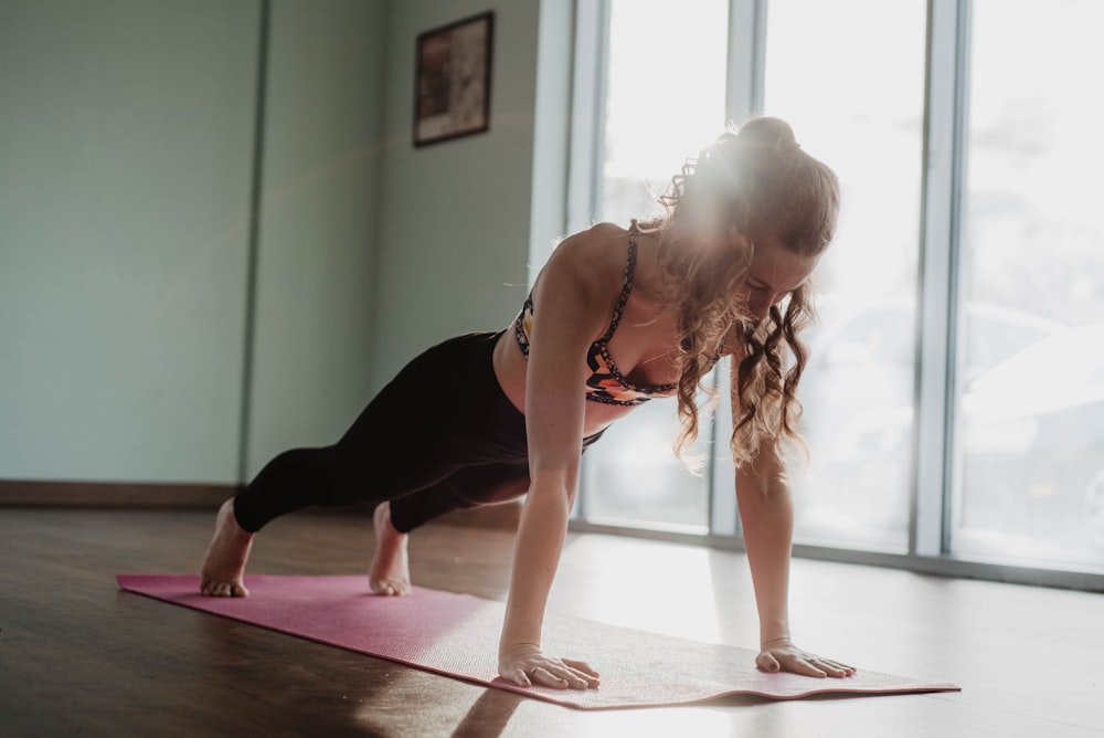 Mujer con camiseta negra sin mangas y leggings negros haciendo yoga