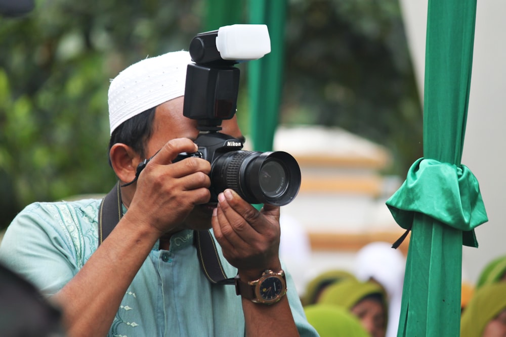 man in blue button up shirt holding black dslr camera