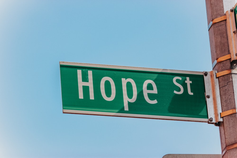 a green street sign hanging from the side of a building