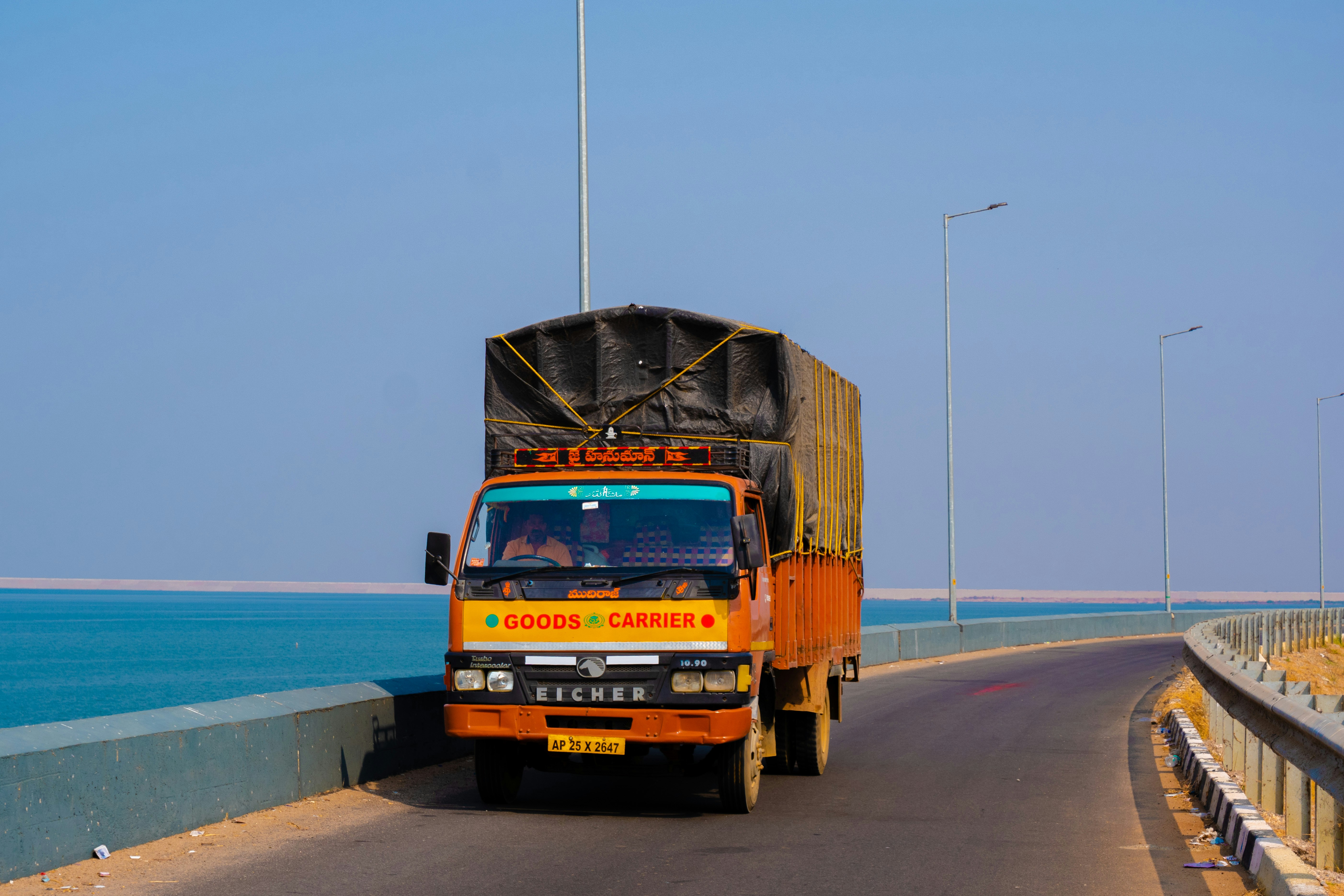 orange and black truck on road near sea during daytime