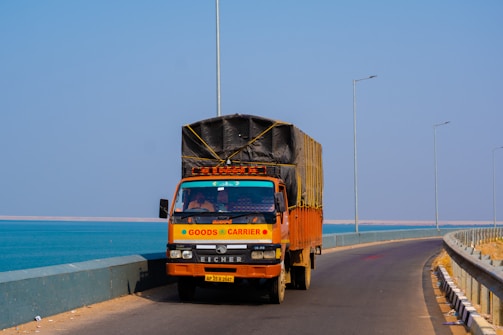 orange and black truck on road near sea during daytime