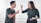 Two people are standing and pointing fingers at each other, seemingly engaged in a heated argument. Both are wearing casual gray shirts, and their expressions suggest anger or frustration.