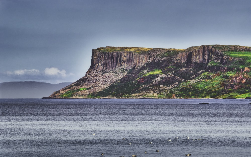 brown and green mountain beside body of water during daytime