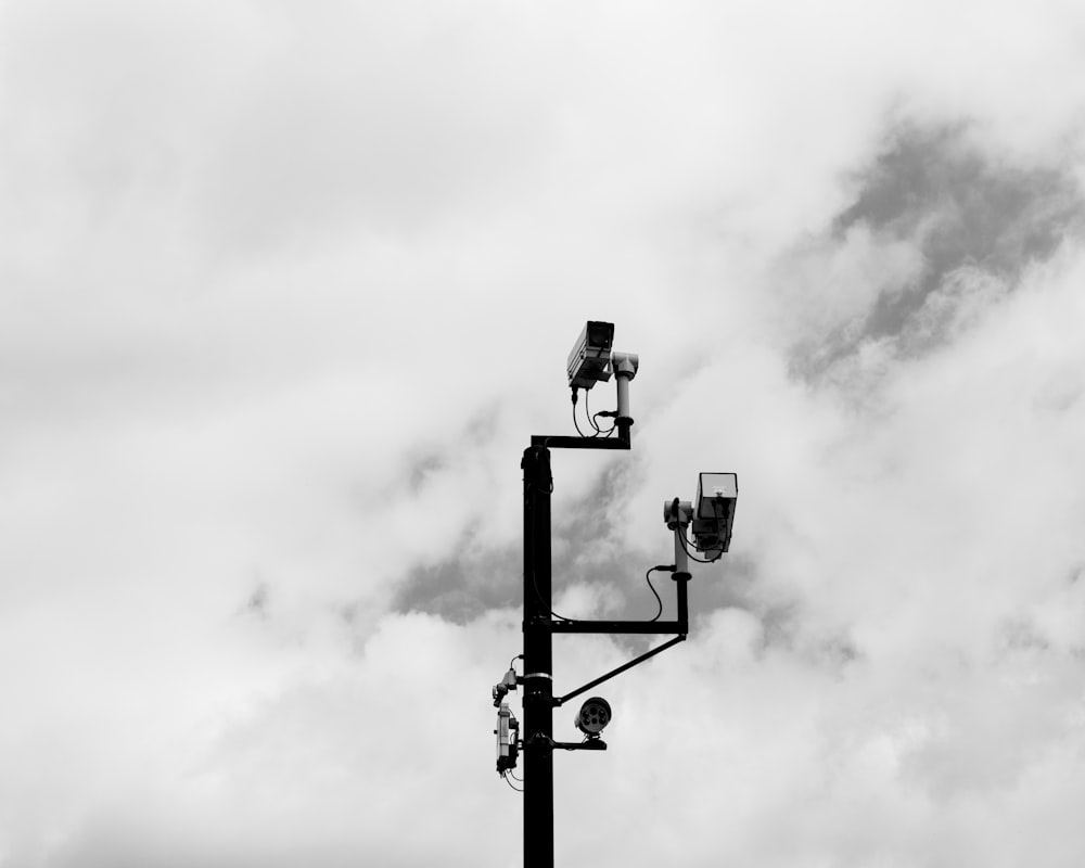 grayscale photo of street light under cloudy sky