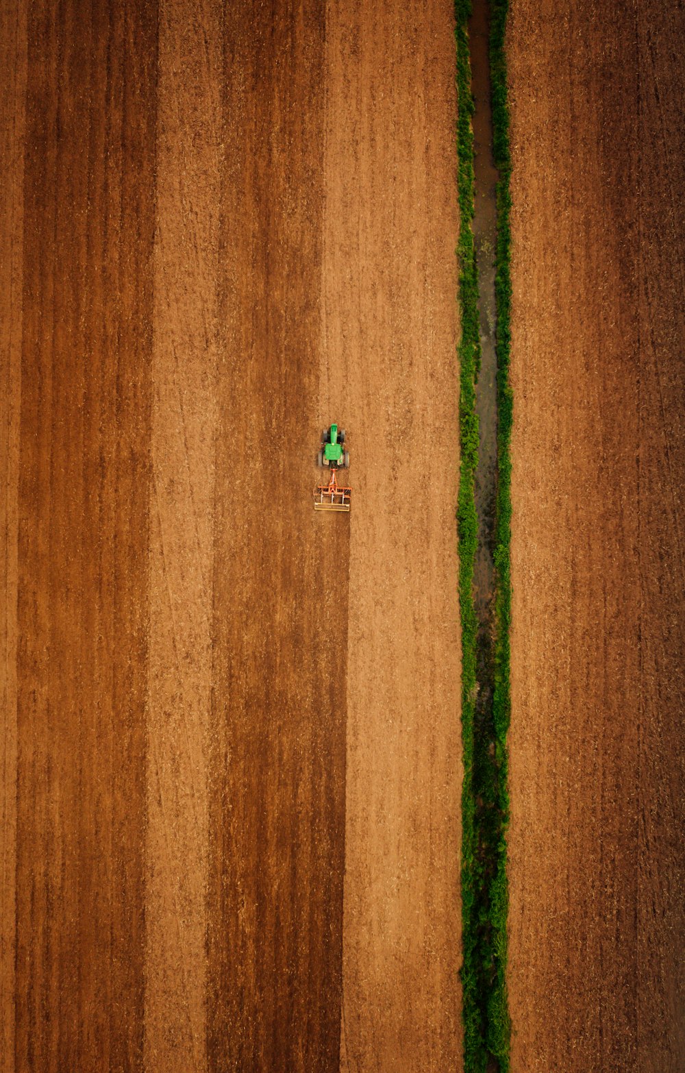 una veduta aerea di un campo arato con un trattore