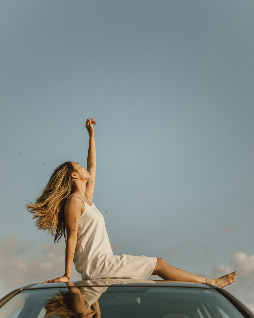 woman in white sleeveless dress raising her right hand