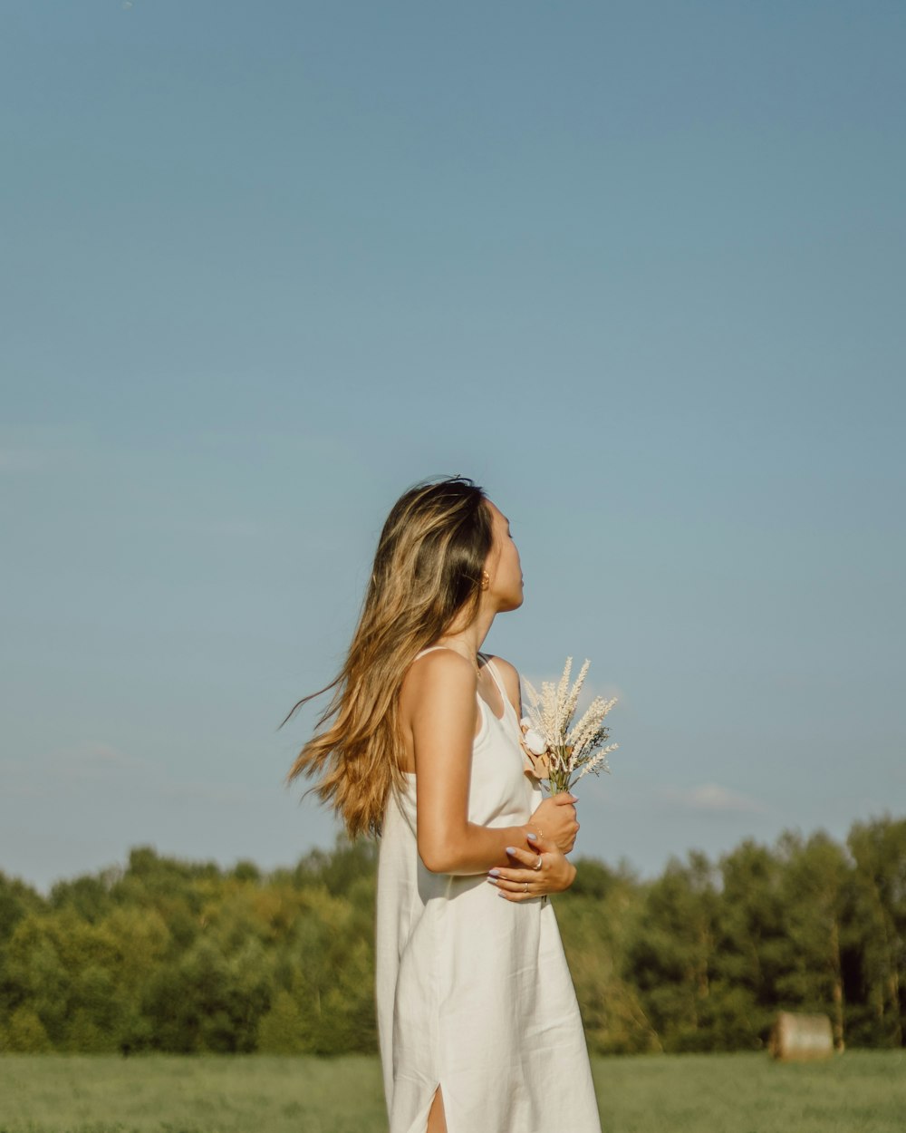 donna in vestito bianco che tiene il fiore bianco