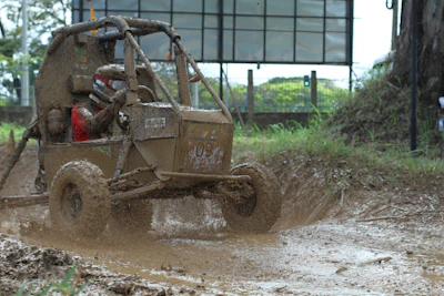 A sleek UTV driving through muddy terrain with splashes of water.