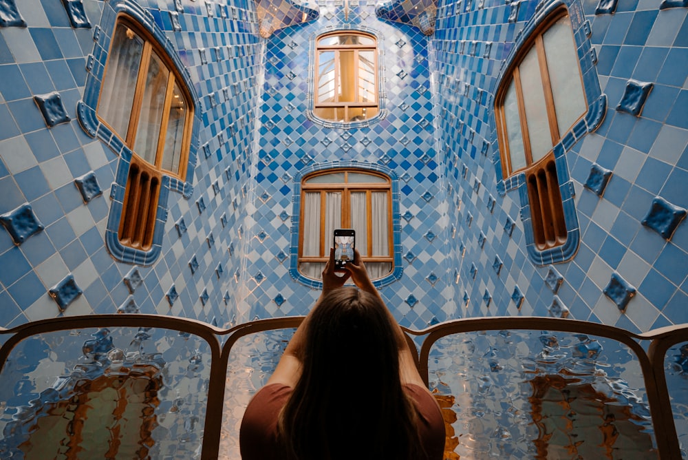 Femme en veste noire debout devant un bâtiment en béton brun et bleu