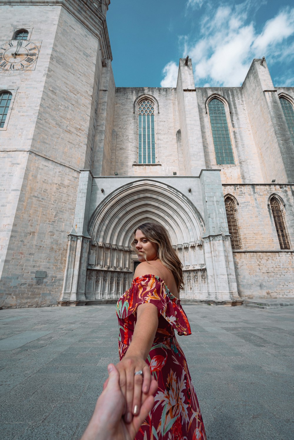 woman in red and white floral dress standing near brown brick building during daytime