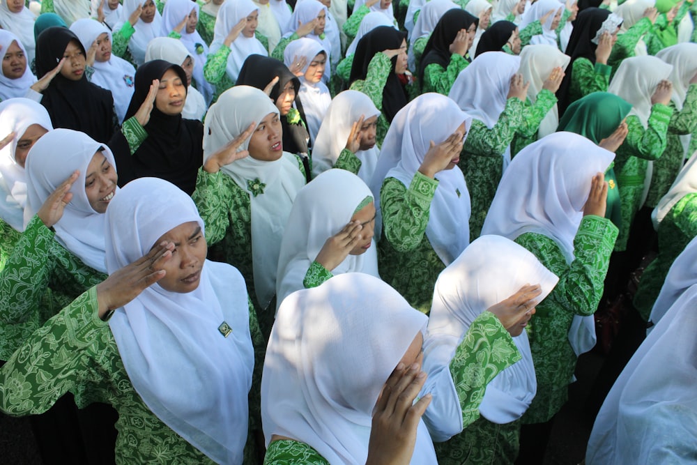 Menschen im weißen Hijab stehen tagsüber auf grünem Rasen