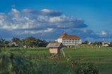 brown and white house on green grass field under blue sky during daytime