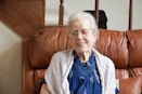 woman in blue shirt and gray cardigan sitting on brown sofa