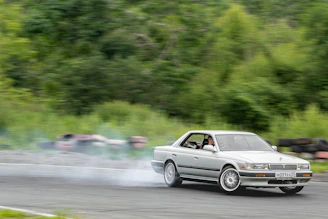 Close-up of a sleek drift car tire smoking on asphalt during a sharp turn on a mountain road.