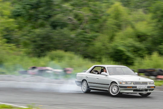 Close-up of a sleek drift car tire smoking on asphalt during a sharp turn on a mountain road.