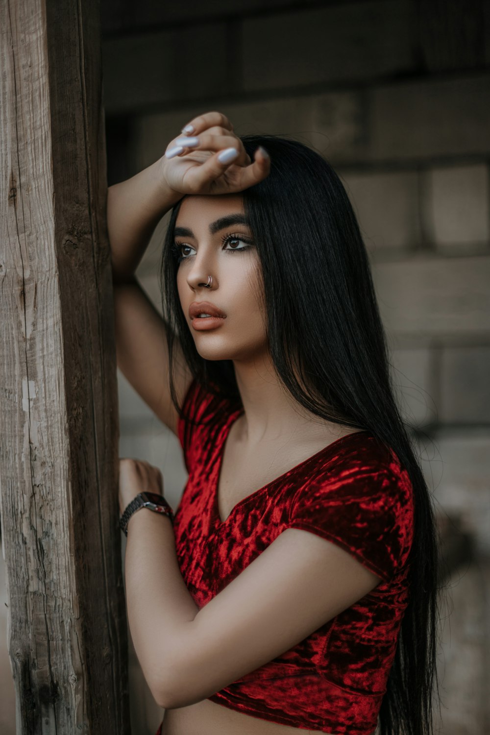 woman in red sleeveless top leaning on brown wooden post