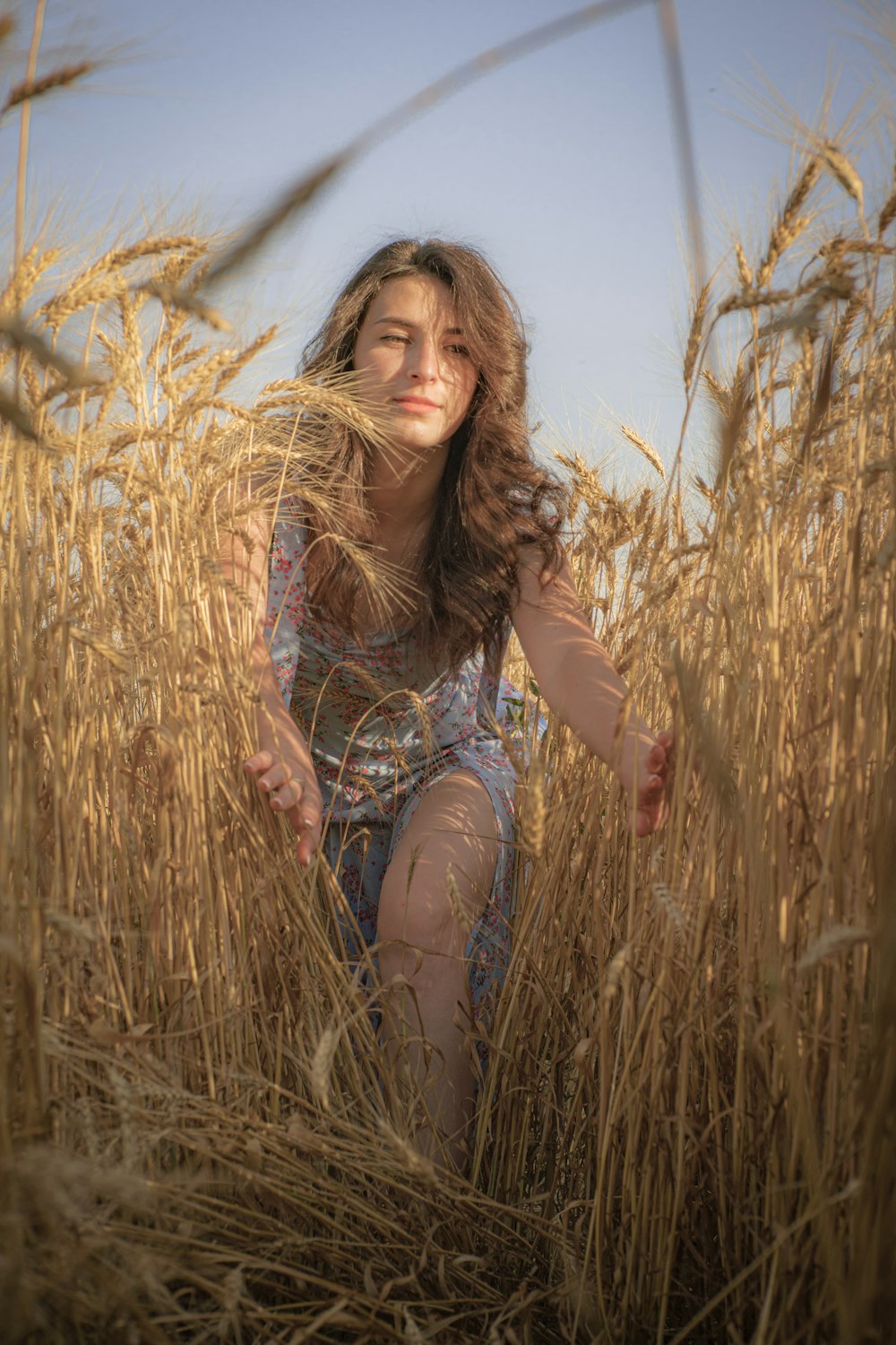 woman in blue denim shorts sitting on brown grass during daytime