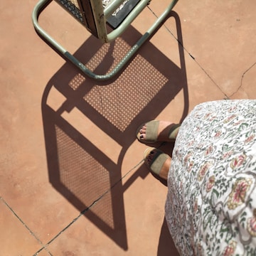 Close-up of colorful summer sandals resting on sunlit terracotta tiles.