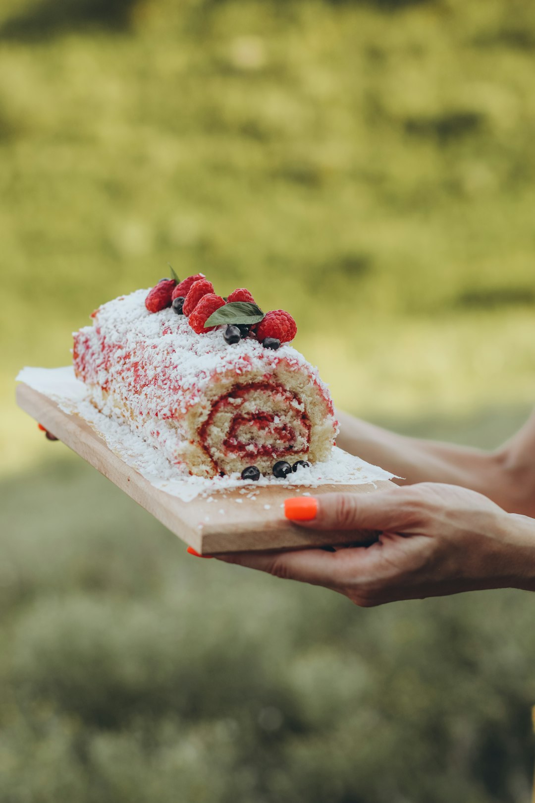 person holding white and red cake