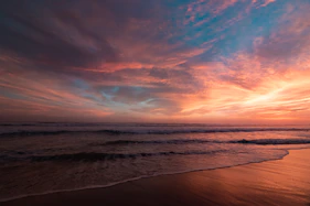 body of water under cloudy sky during sunset