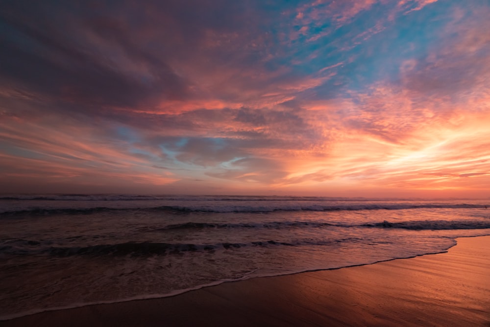 body of water under cloudy sky during sunset