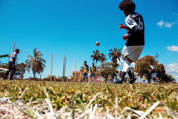 man in black and white jersey shirt and black pants playing soccer during daytime