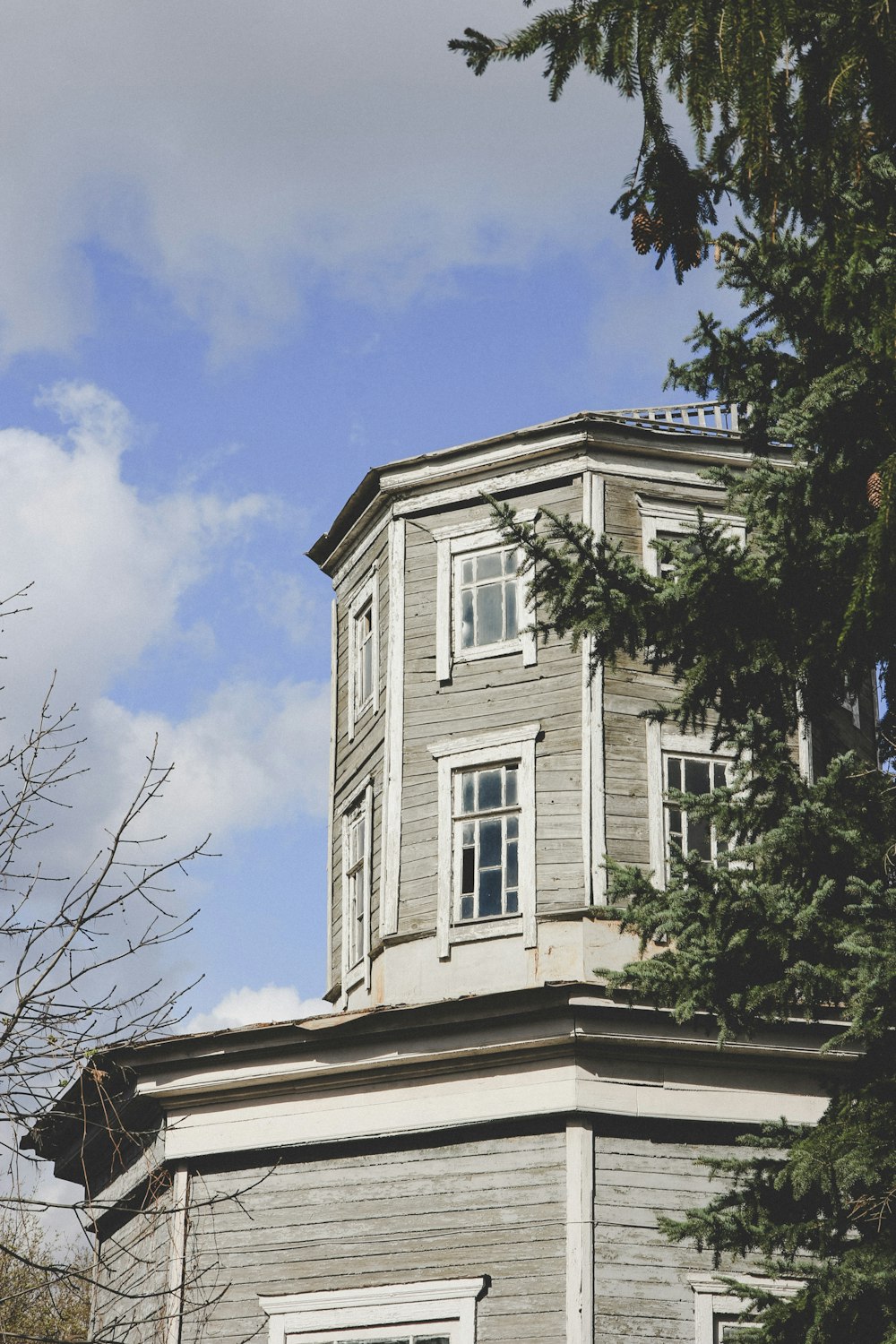 Weißes Betongebäude in der Nähe von kahlen Bäumen unter blauem Himmel tagsüber