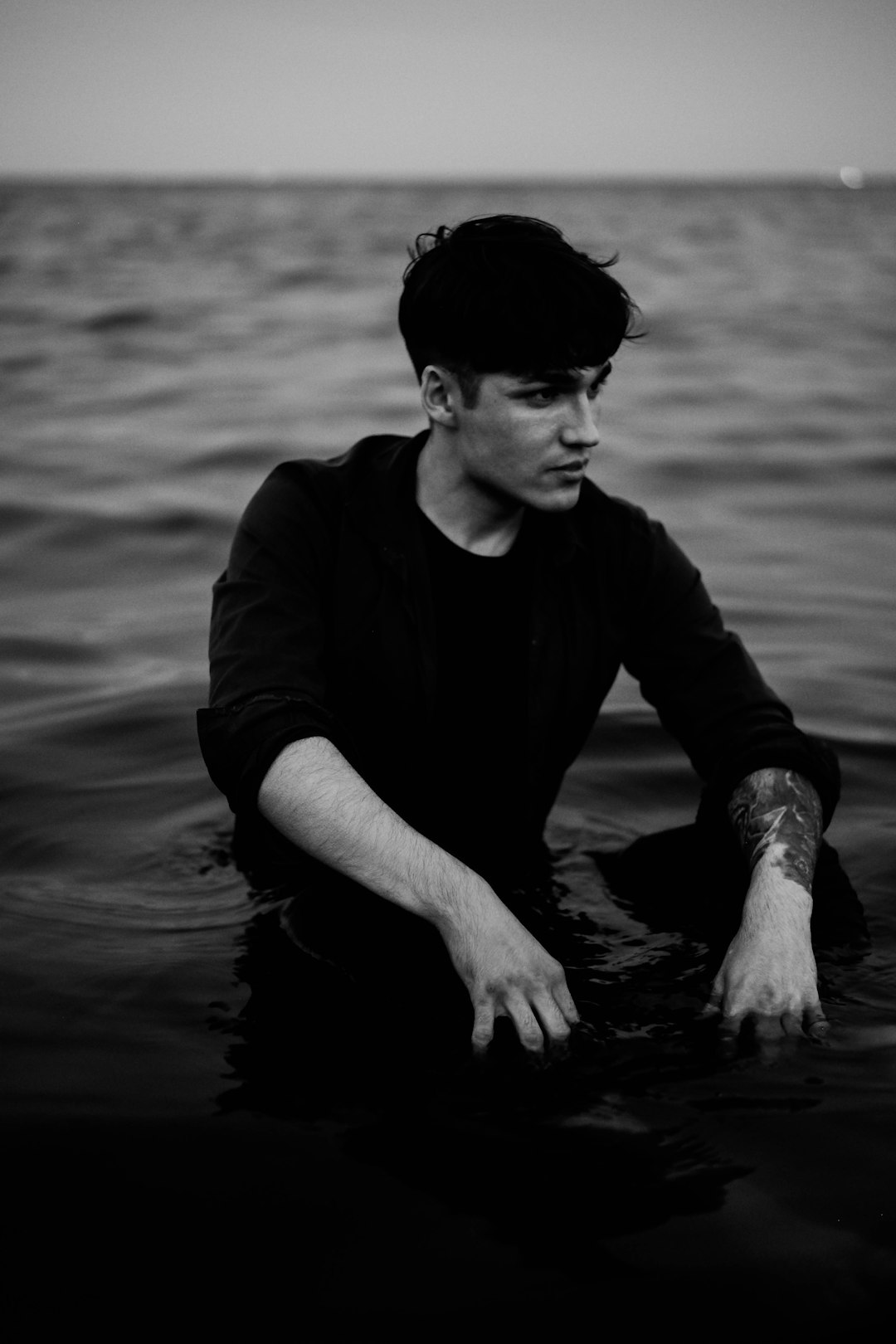 man in black long sleeve shirt sitting on water