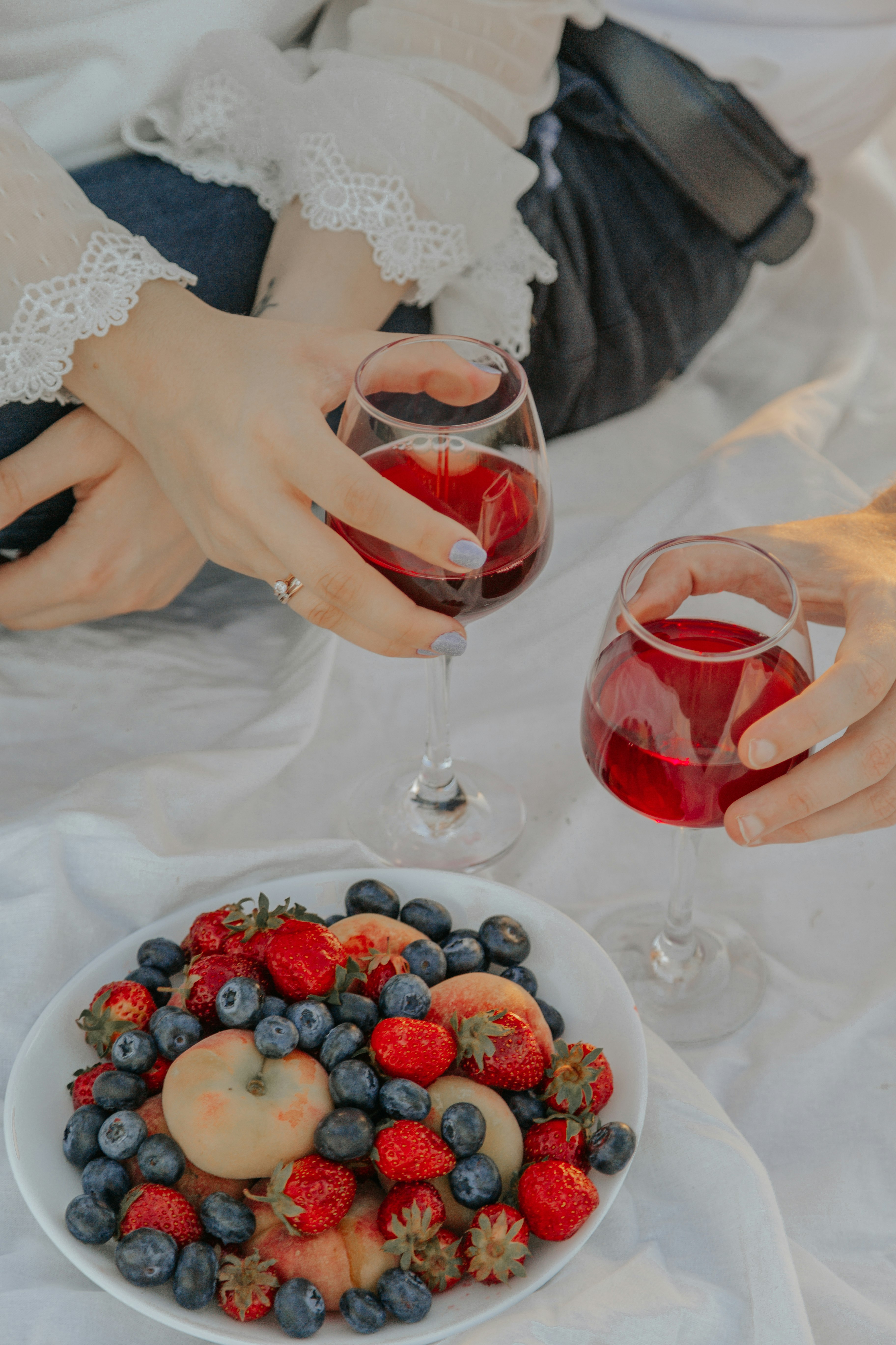 woman in white wedding dress holding red wine glass with red liquid