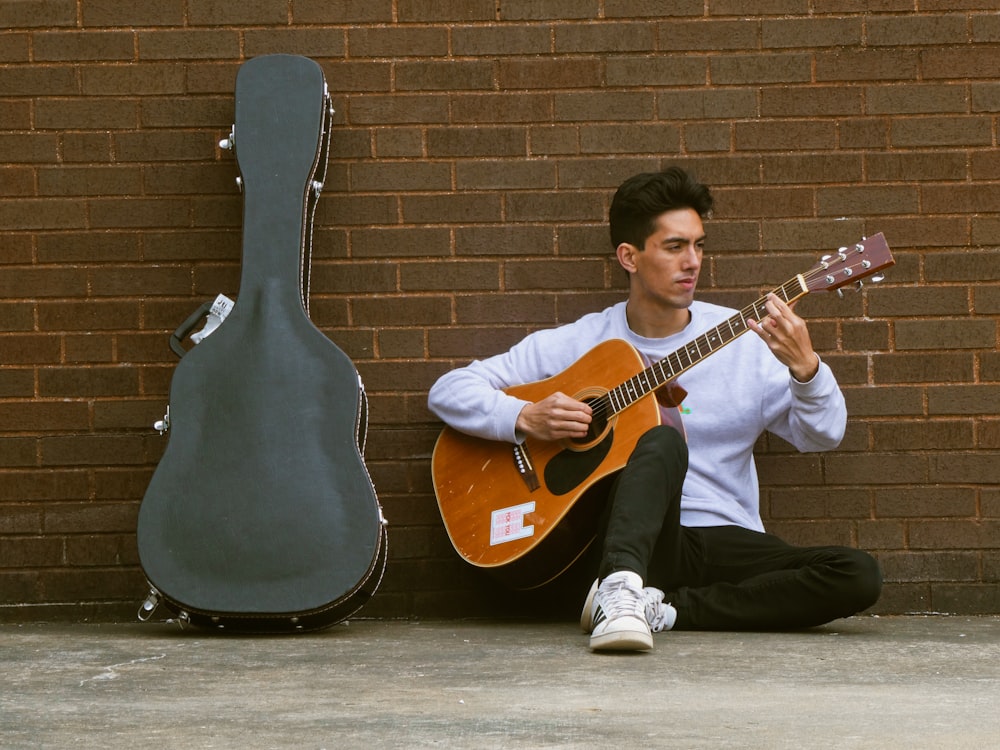 man in white shirt playing acoustic guitar