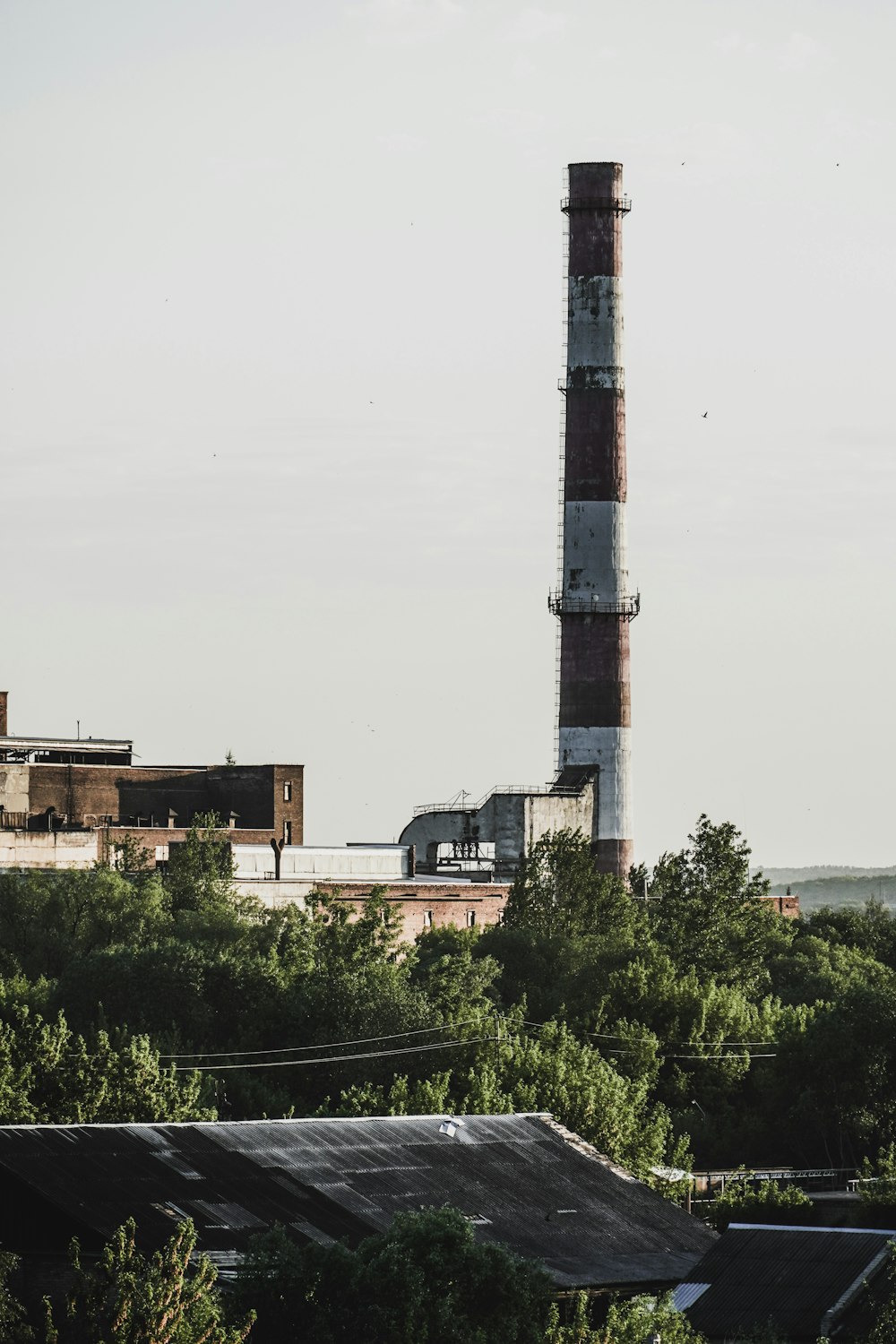 weißer und schwarzer Turm in der Nähe grüner Bäume unter weißem Himmel tagsüber