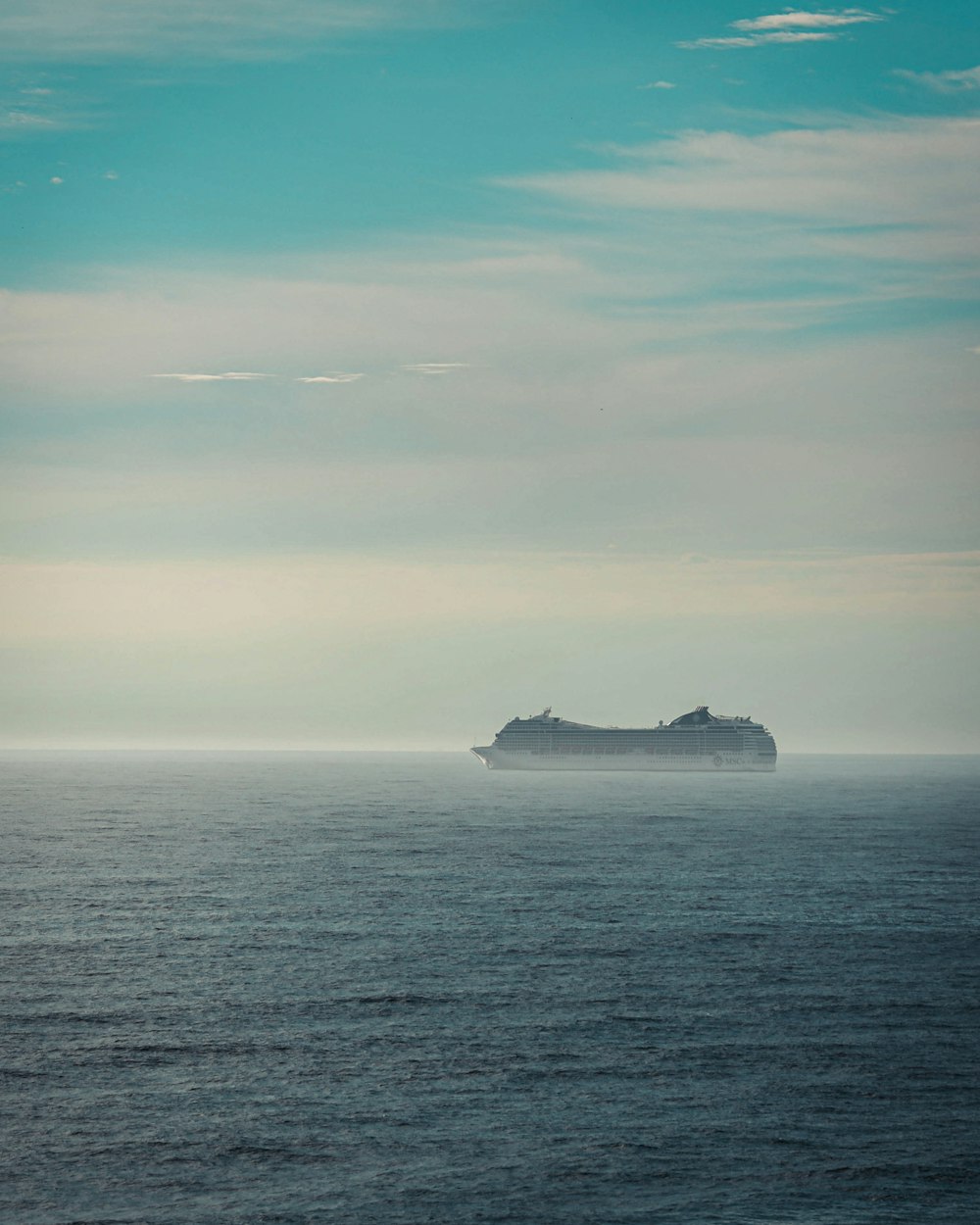 black and white ship on sea under white clouds and blue sky during daytime