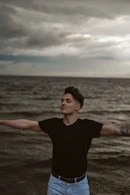 man in black crew neck t-shirt standing on beach during daytime