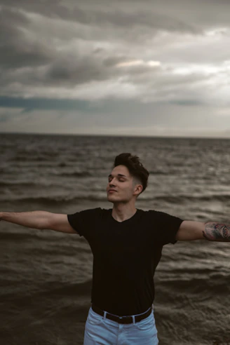 man in black crew neck t-shirt standing on beach during daytime