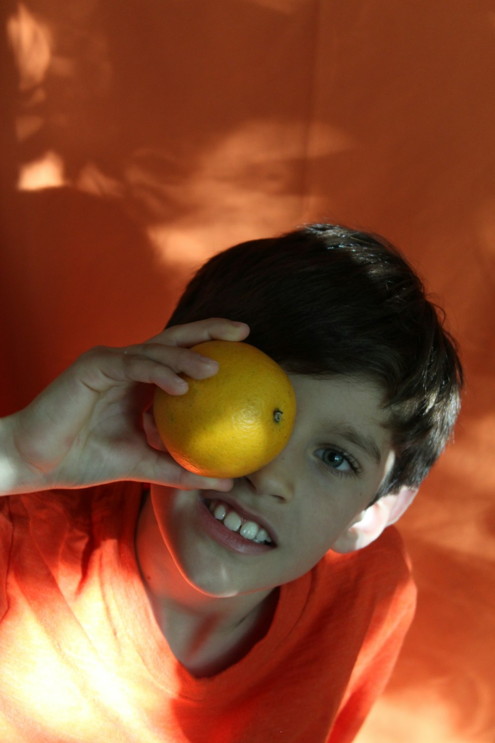 黄色い果物を持つオレンジ色のシャツを着た少年