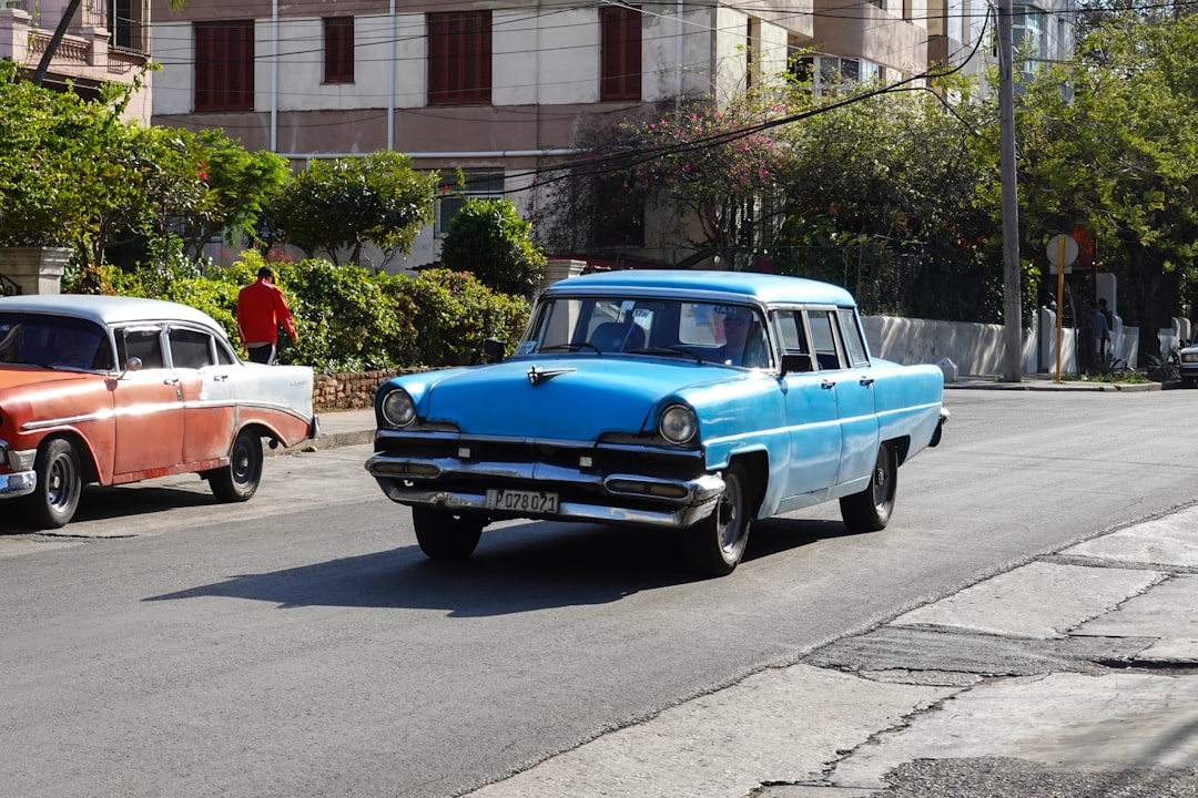 blue and white vintage car parked on sidewalk during daytime