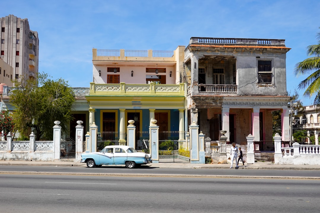 white coupe parked in front of beige concrete building during daytime