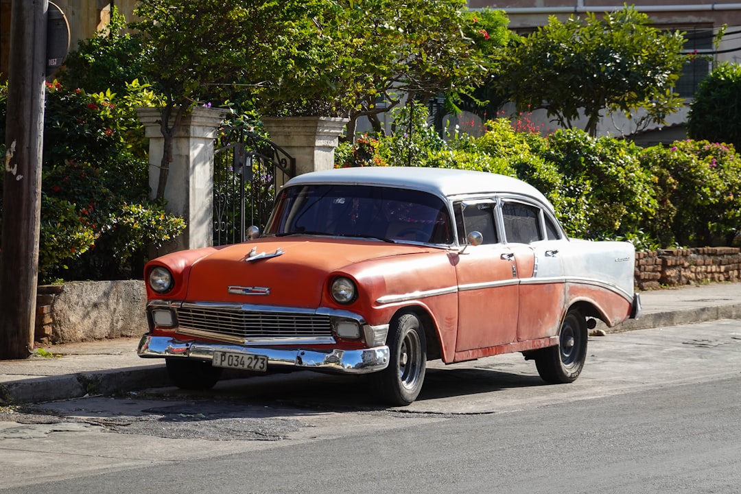 red and white vintage car parked on sidewalk during daytime