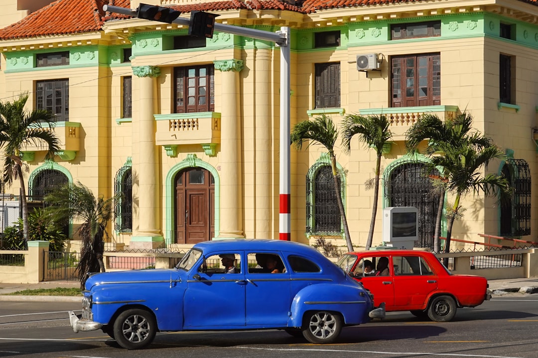 blue sedan parked beside beige concrete building during daytime