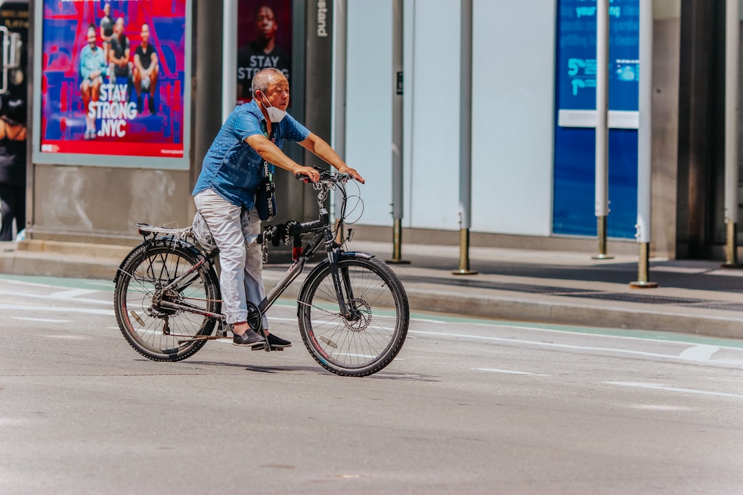 man in blue polo shirt riding black bicycle on road during daytime