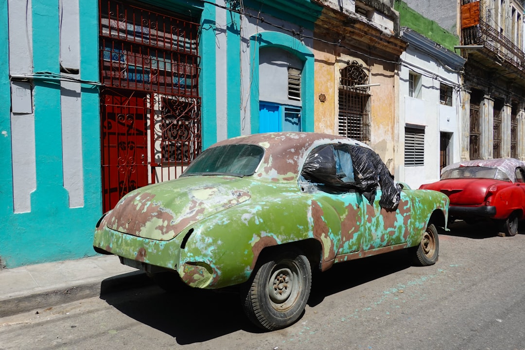 green and white car parked beside building during daytime